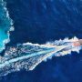 aerial photo of a power boat coursing through blue mildly choppy water